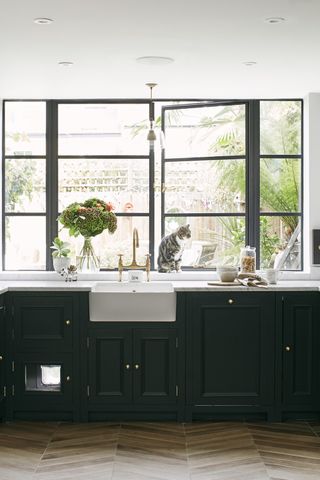 Dark green kitchen cabinets and sink with a window