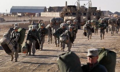 U.S. Army soldiers carry their bags to shipping containers as they prepare to leave their Iraqi base: All American troops will withdraw from Iraq by the end of the year.