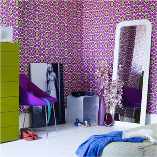 bedroom with magenta and lime wallpaper on wall and large mirror with white flooring