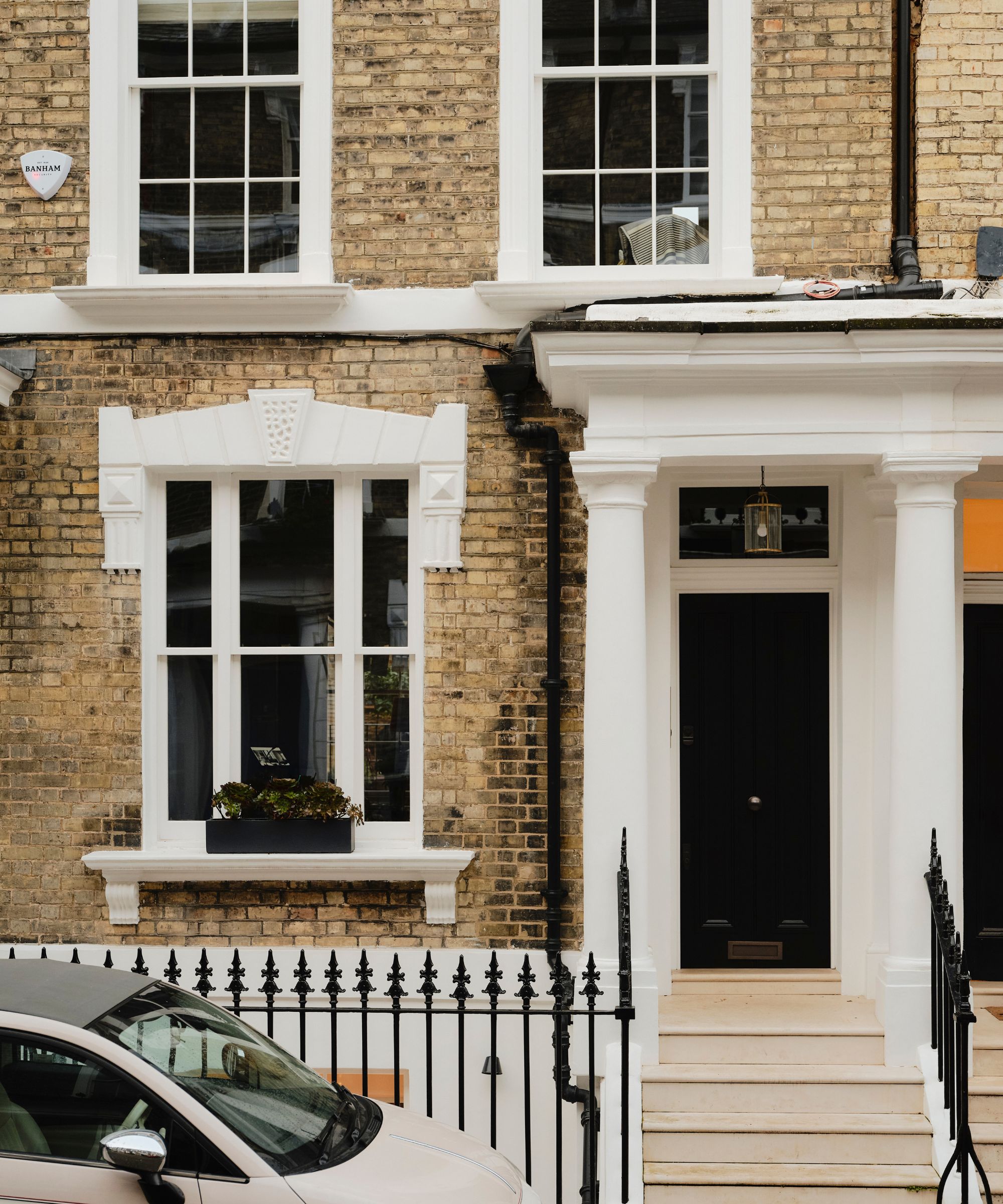 Exterior of a Georgian townhouse with pale bricks and white accents with a black front door