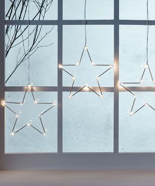 christmas window decoration with light-up stars hanging against the glass panes