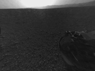This full-resolution version of one of the first images taken by a rear-left Hazard-Avoidance camera on NASA's Curiosity rover, was released on Aug. 6, 2012.The image was originally taken through the "fisheye" wide-angle lens, but has been "linearized" so that the horizon looks flat rather than curved. Part of the rim of Gale Crater can be seen from the top-middle to the top-right of the image, and one of the rover's wheels is pictured at the bottom right.