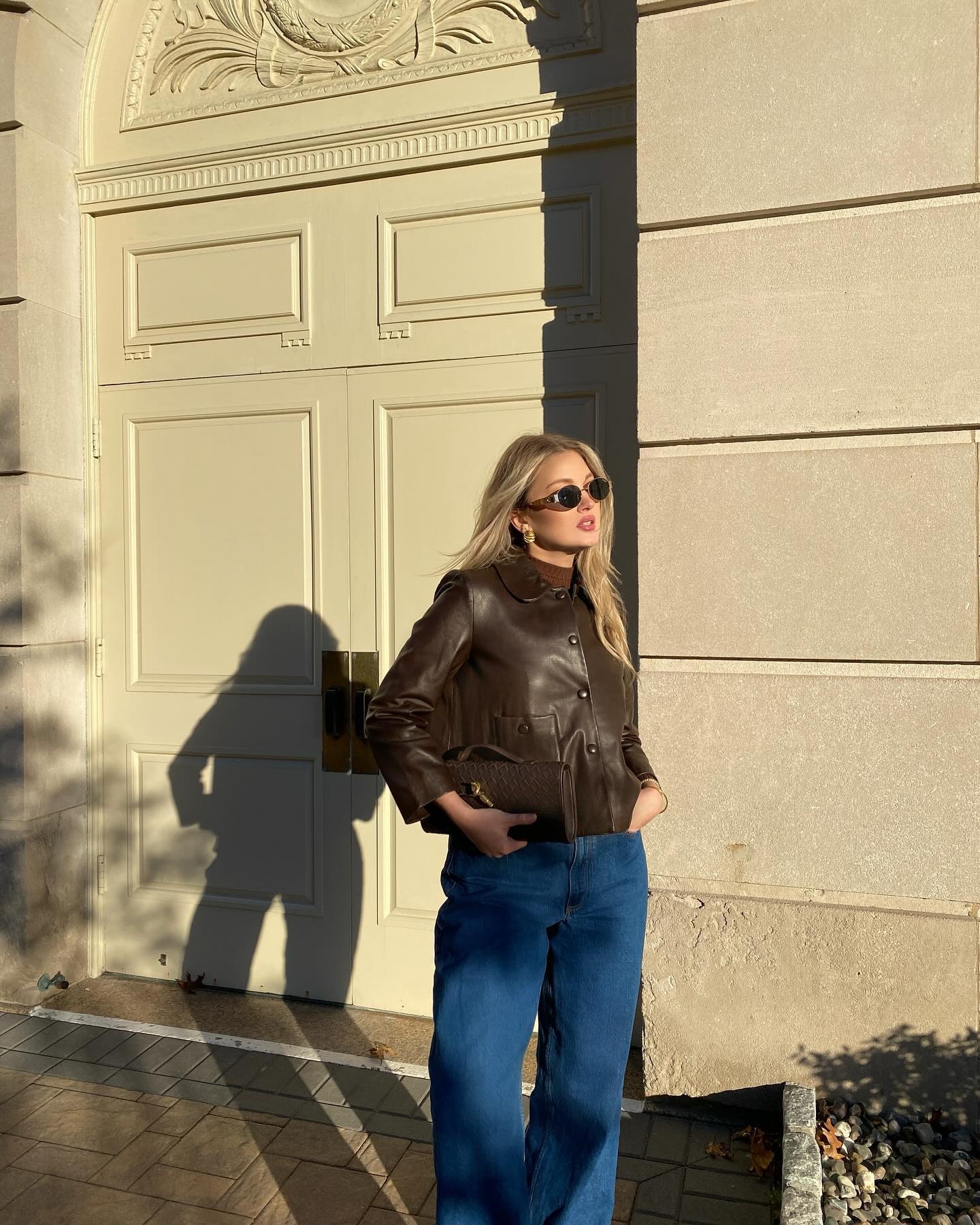 A woman posing outside in a chocolate brown leather jacket