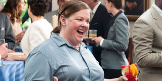 Melissa McCarthy laughing, with a drink in her hand, in Bridesmaids.