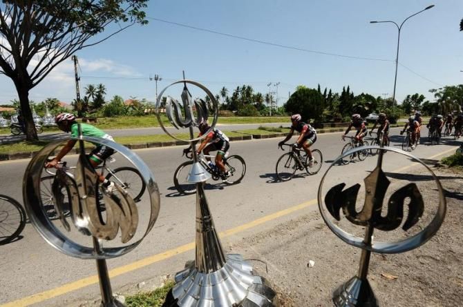 Riders pass Mosque top ornament seller during Stage 6 Tour de Singkarak 2013