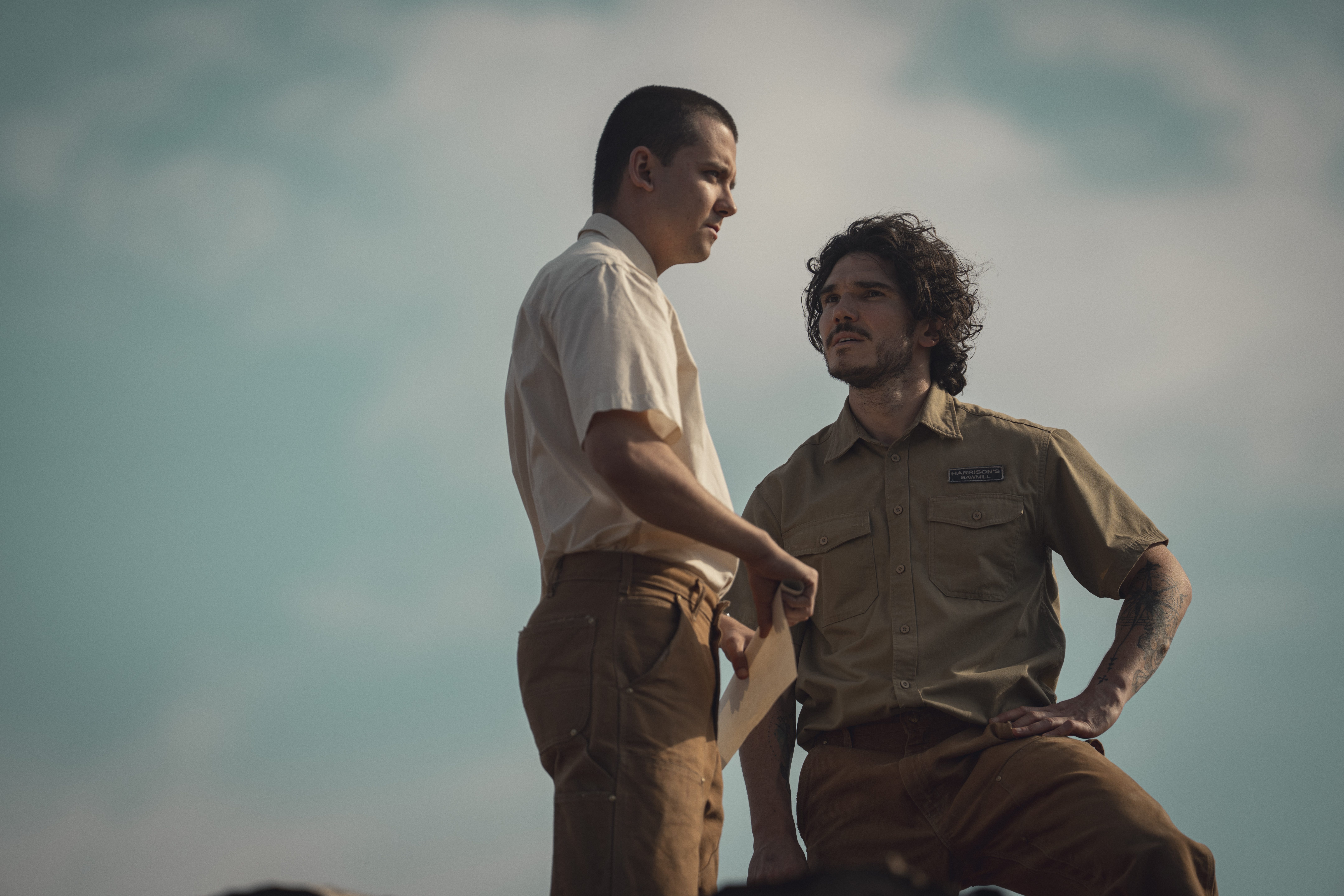 sam and adam stand together against a blue cloudy sky in a still from unchosen