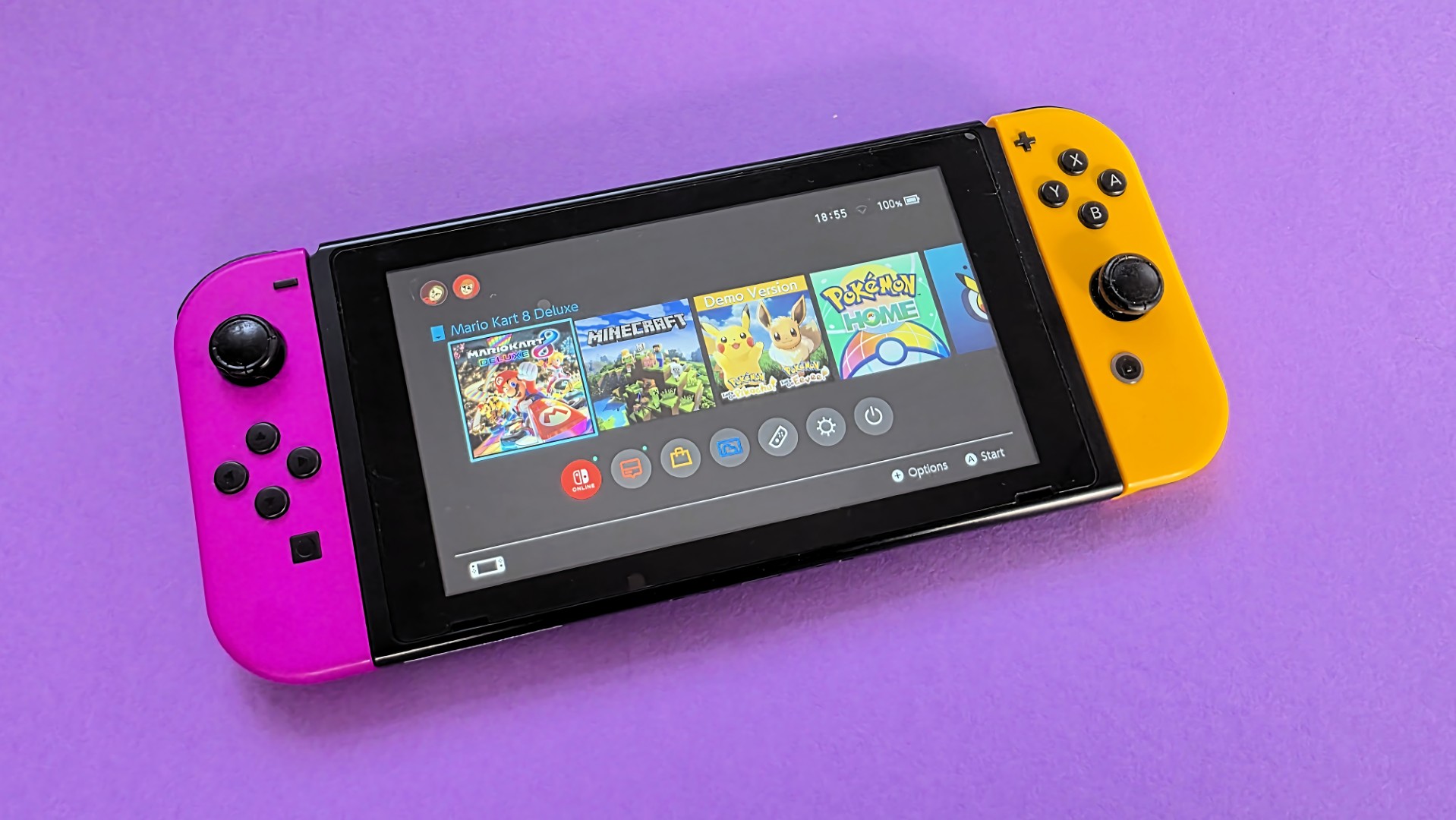 A Nintendo Switch console on a solid purple background, featuring one pink Joy&amp;#8209;Con and one orange Joy&amp;#8209;Con