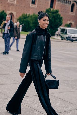 Fashion week spring/summer 2024 attendee wearing black fur jacket and black striped trousers