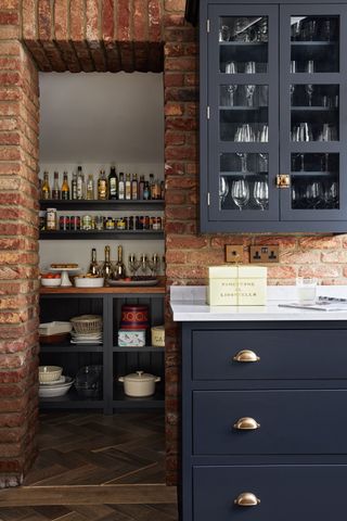 A kitchen with exposed brick walls and blue cabinetry