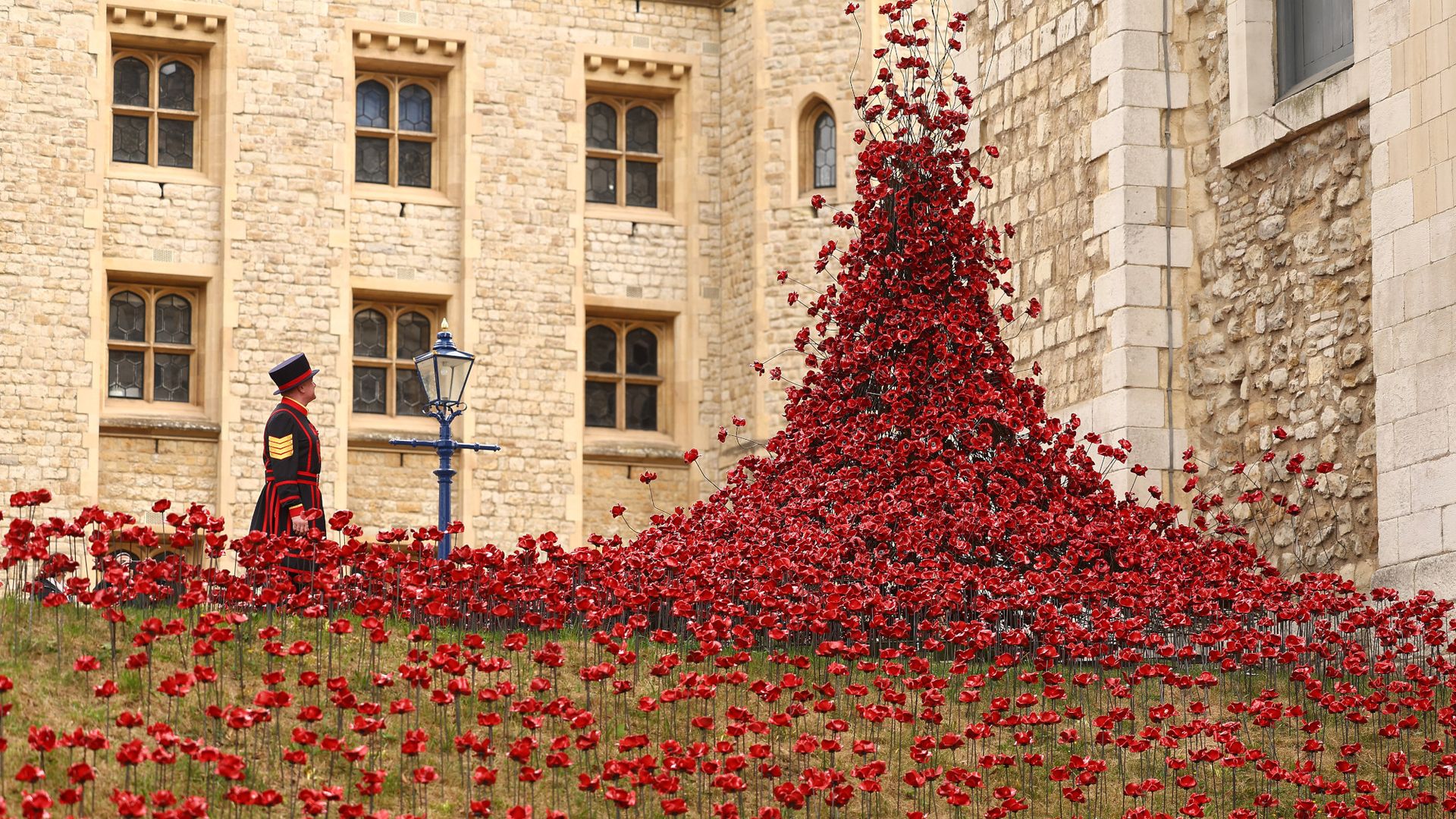 
                                Sergeant Daniel Benson, the Yeoman Warder, stands beside &quot;The Tower Remembers&quot; floral display in London, England
                            