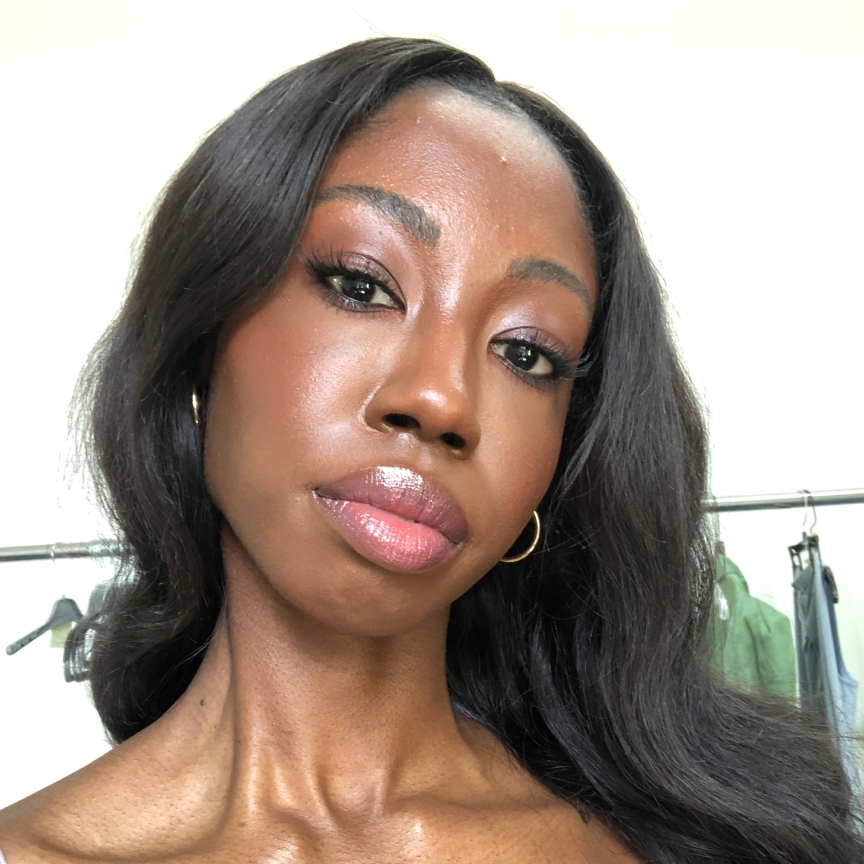 a black woman with hoop earrings and long dark hair and pink lipstick