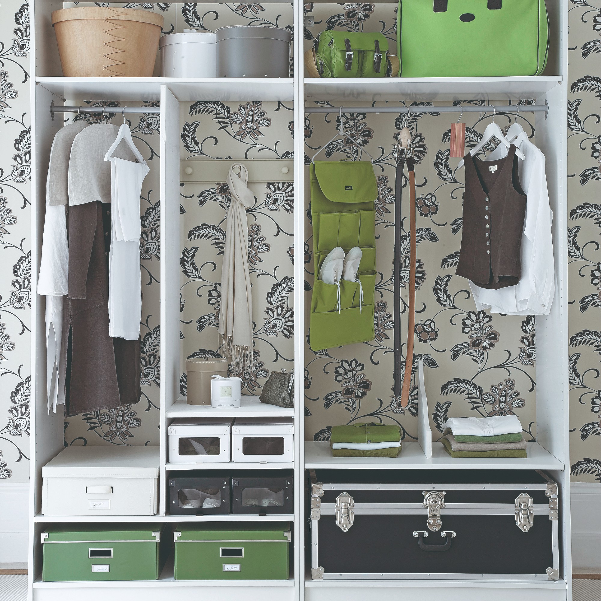 A tidy and organised wardrobe against a floral wallpaper