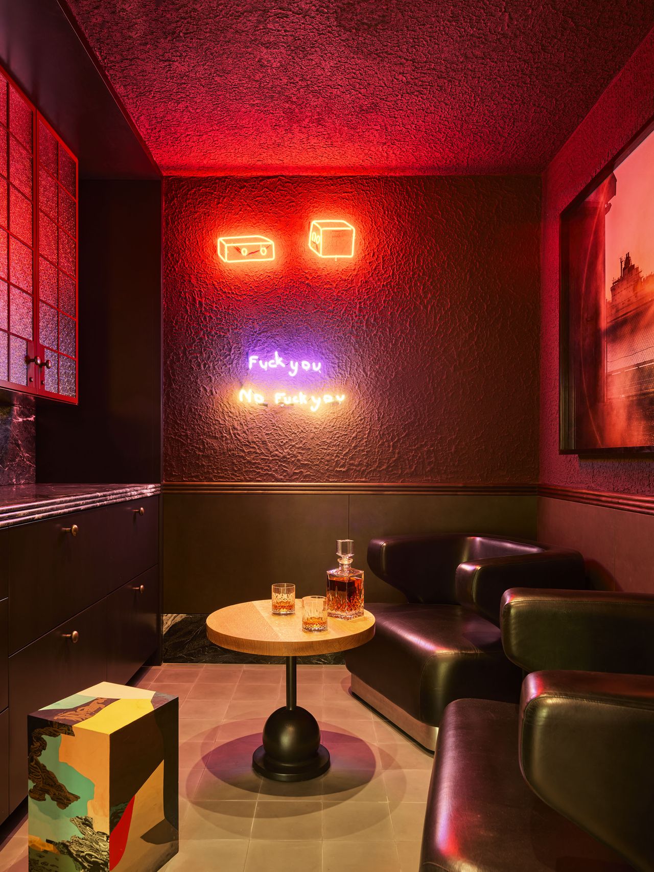 cellar bar room with neon lights on the wall, two leather armchairs, and a coffee table
