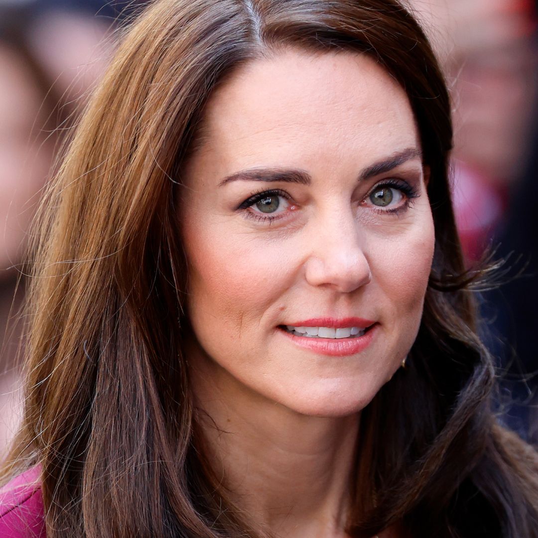 Kate Middleton has long brown hair and is wearing a pink dress