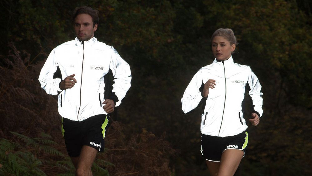 Man and woman running in reflective Proviz jackets