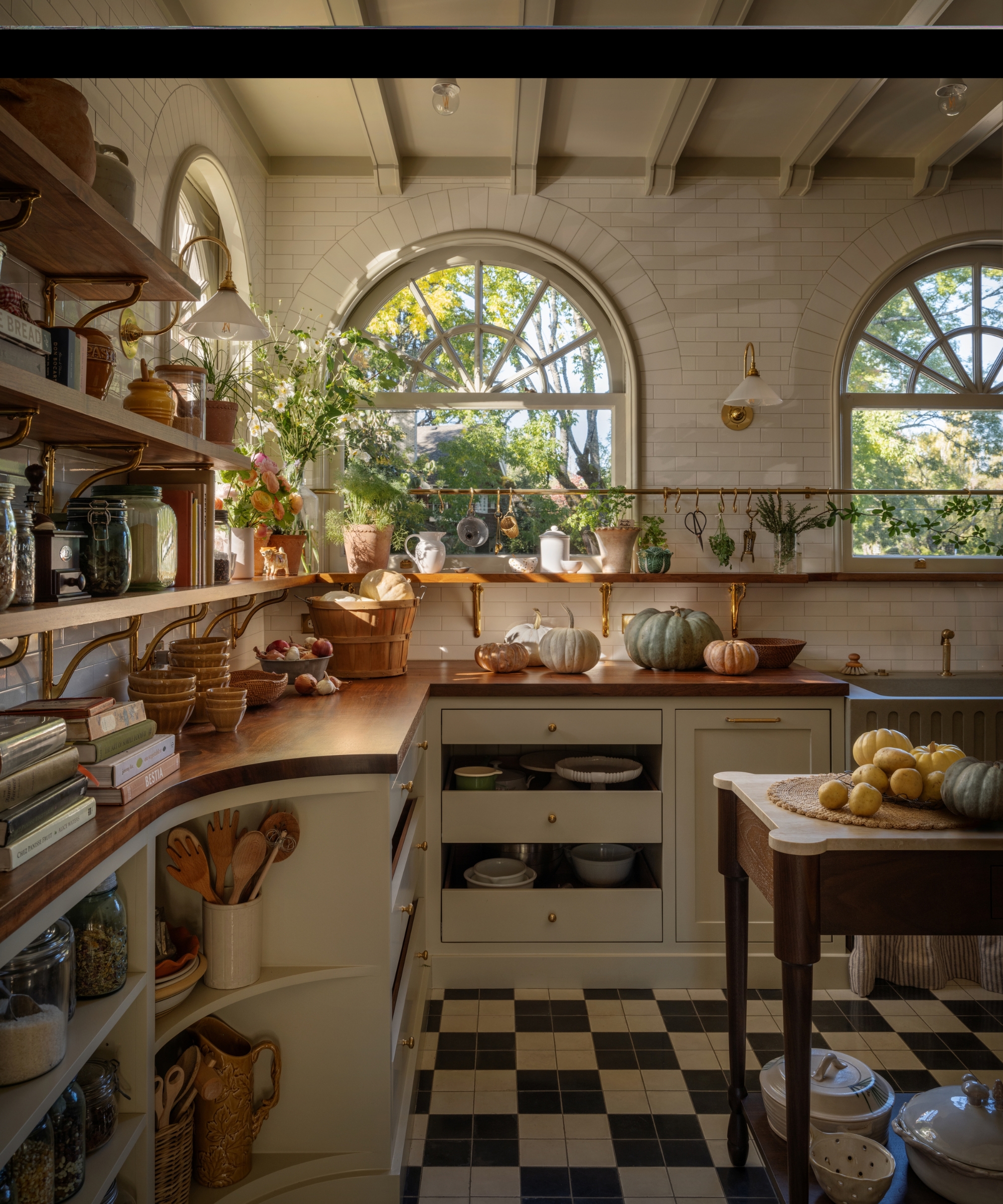 A charming kitchen with white cabinets, white subway tiled walls, a wooden freestanding island, wood countertops, and open storage