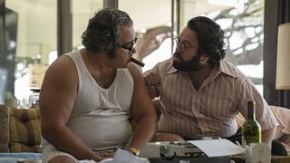 Patrick Gallo sits next to Dan Fogler on a couch in The Offer