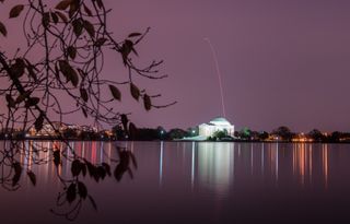 A Northrop Grumman Antares rocket appears to streak over the Thomas Jefferson Memorial in Washington, D.C. after successfully launching the Cygnus NG-10 cargo ship toward the International Space Station from Pad-0A at NASA's Wallops Flight Facility on Wal