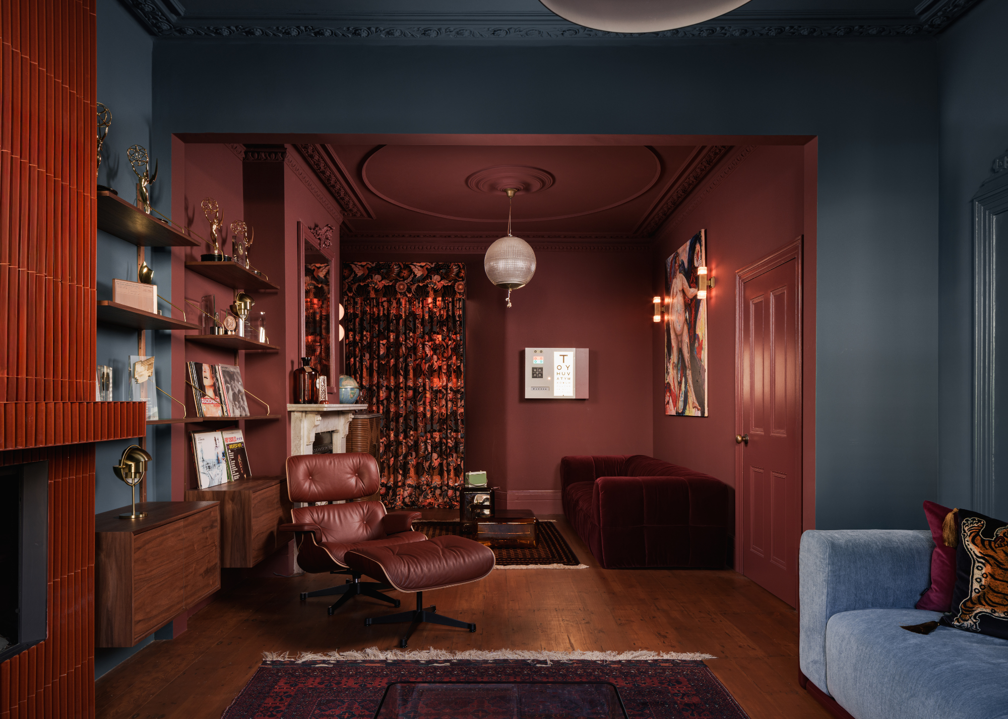 Living spaces zoned with color; one painted teal and the other a rust brown-red with a fireplace and a sofa in each space