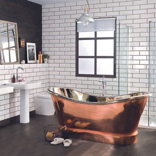 Monochrome bathroom with white tiled walls. copper slipper bath, dark wood plank flooring