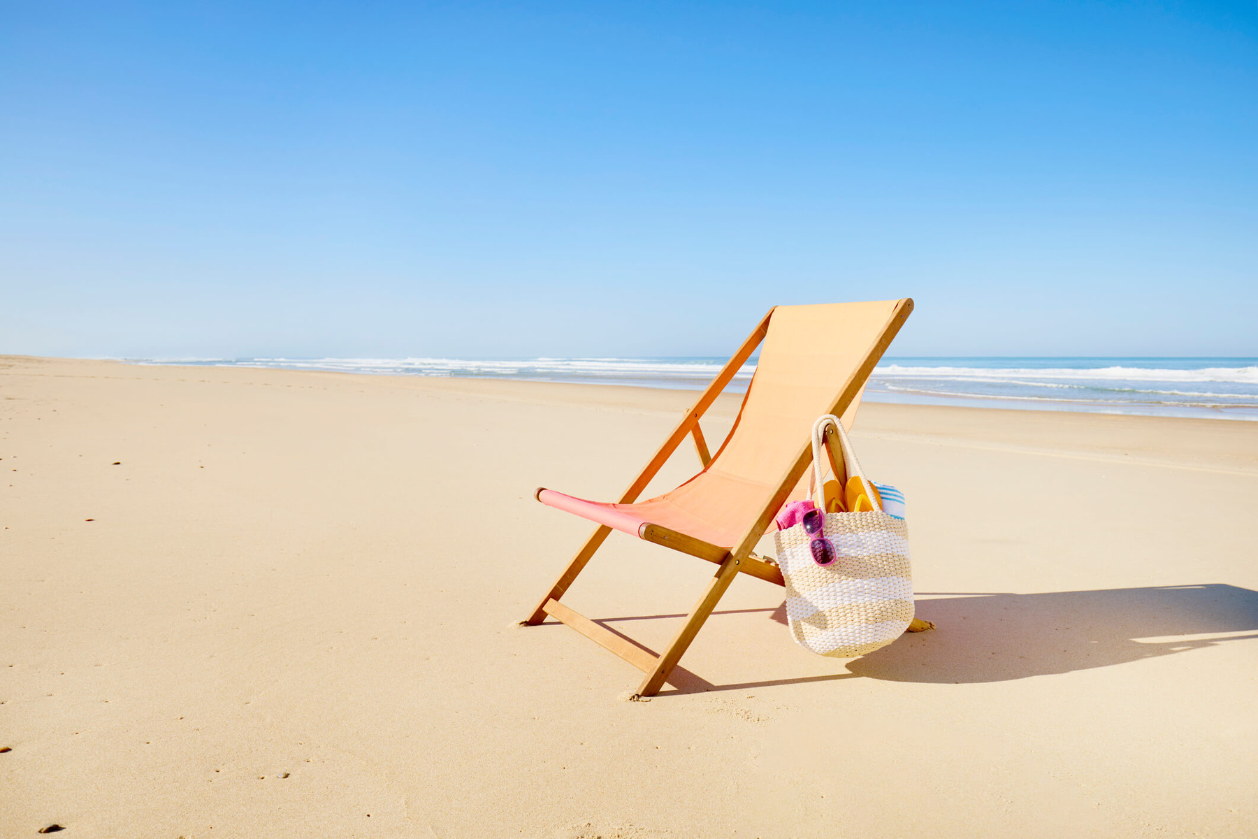A single deck chair is on a quiet beach