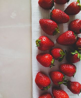 Strawberries laid on a white waffle-textured kitchen tea towel