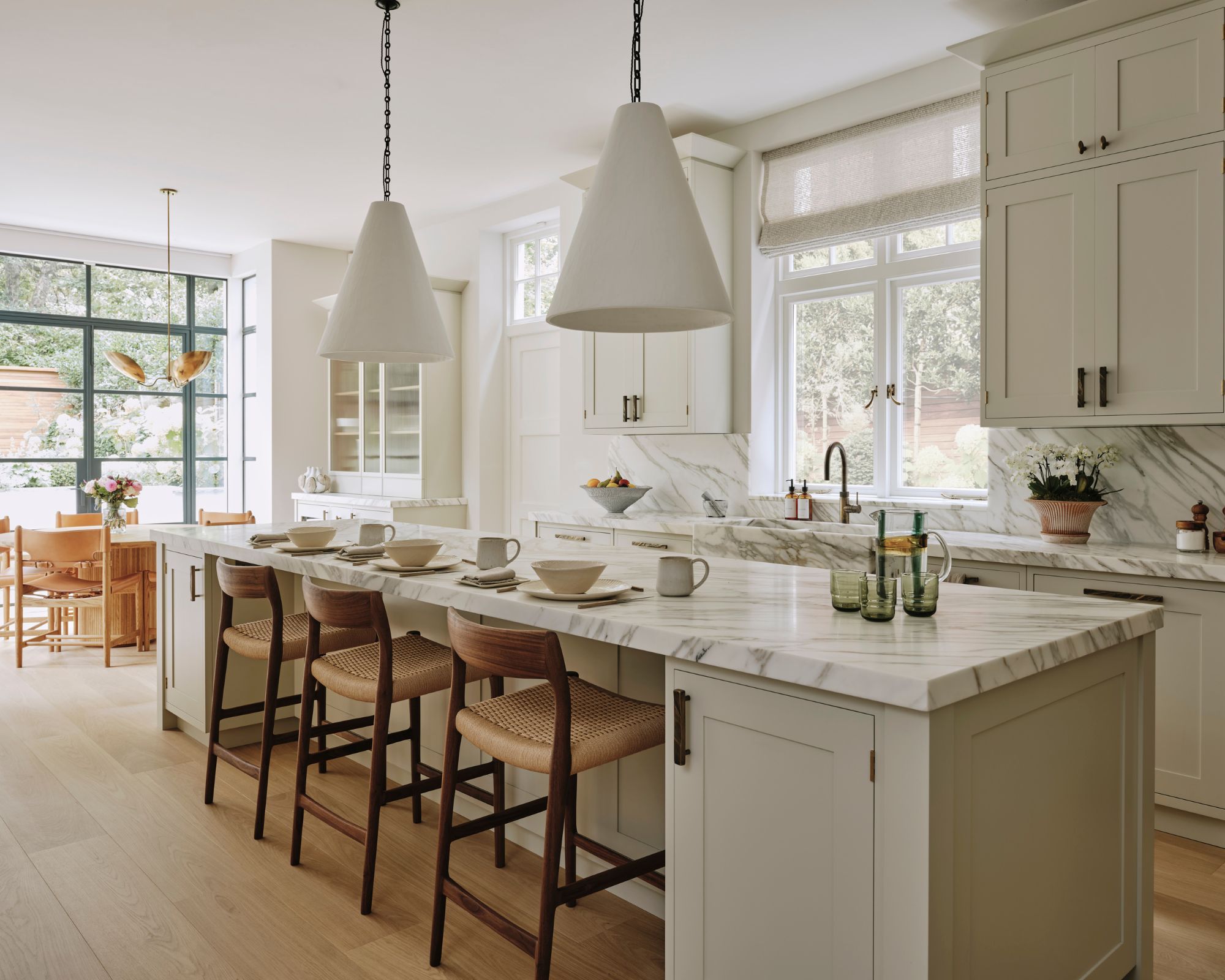 A white shaker-style kitchen with a marble splashback and kitchen island