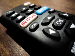 En fjärrkontroller ligger på ett träfärgat bord med en dedikerad Netflix-knapp.
