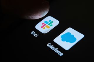 A finger hovering over Slack and Salesforce apps 