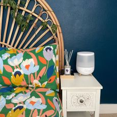 Dunelm humidifier on a white bedside table, in front of a blue painted wall and a bed with floral bedding