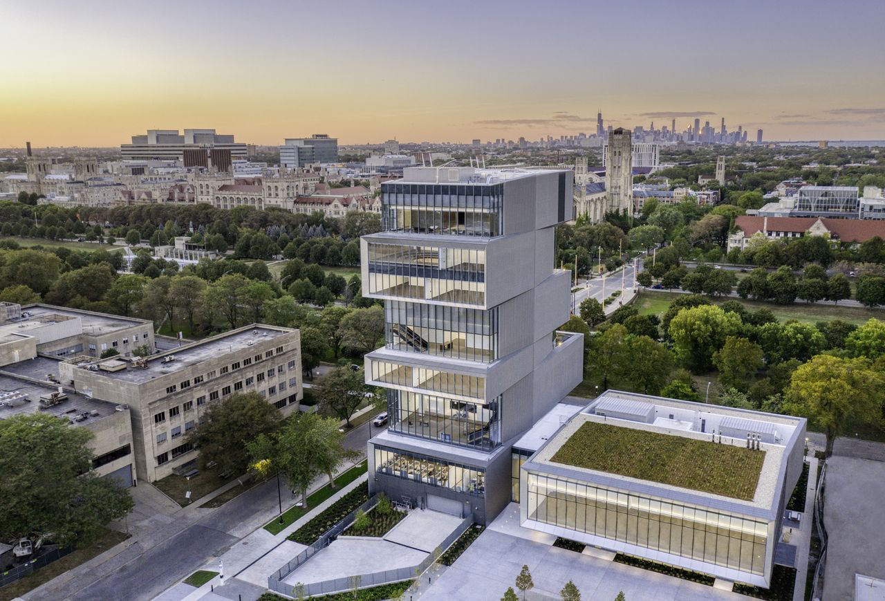 University of Chicago photographer from higher ground. Tall building, that looks like floors are stacked one on top of each other in a zig-zag pattern. Each floor has all-glass walls from one side that provide a panoramic view of the rest of the city.