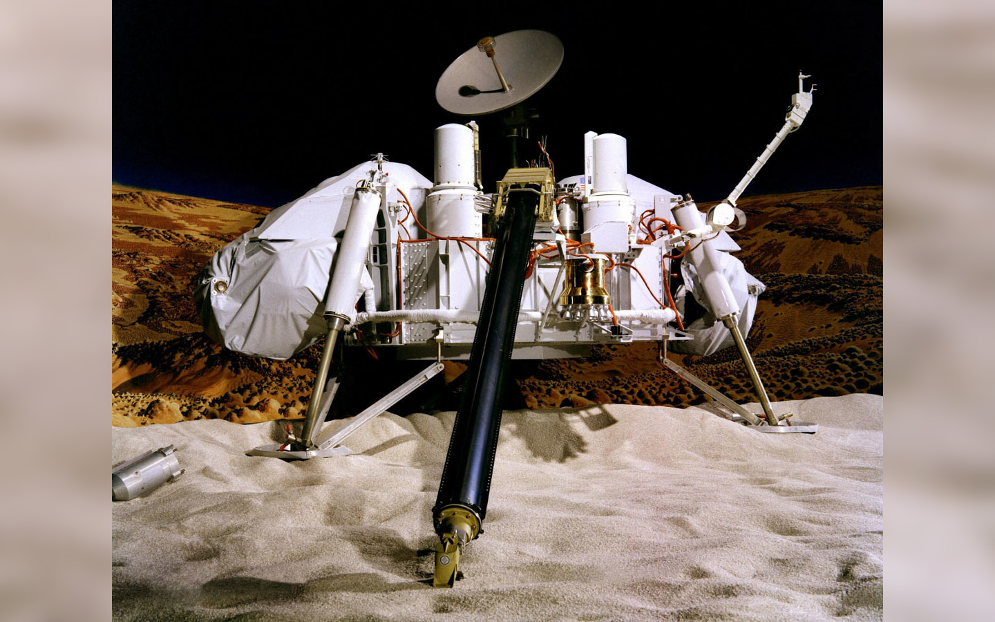 A viking lander photographed against a background showing the surface of Mars.