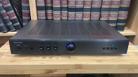 Rotel A8 integrated amplifier on wooden hi-fi rack in front of bookcase