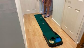 A golfer hits a ball on the PGA Tour Indoor & Outdoor Golf Putting Mat