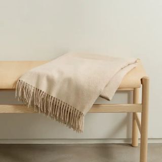 neutral fringed throw on wooden bench