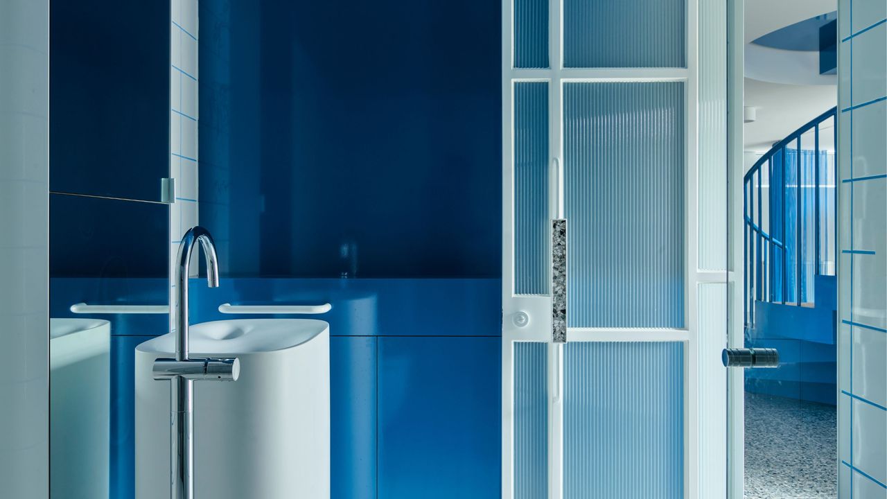 A bathroom with blue gloss paint and a tall sink unit
