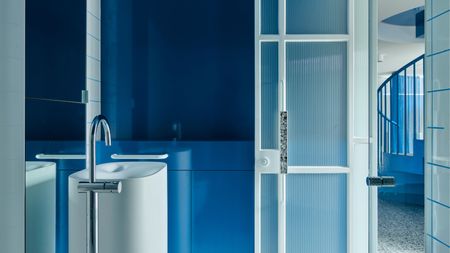 A bathroom with blue gloss paint and a tall sink unit