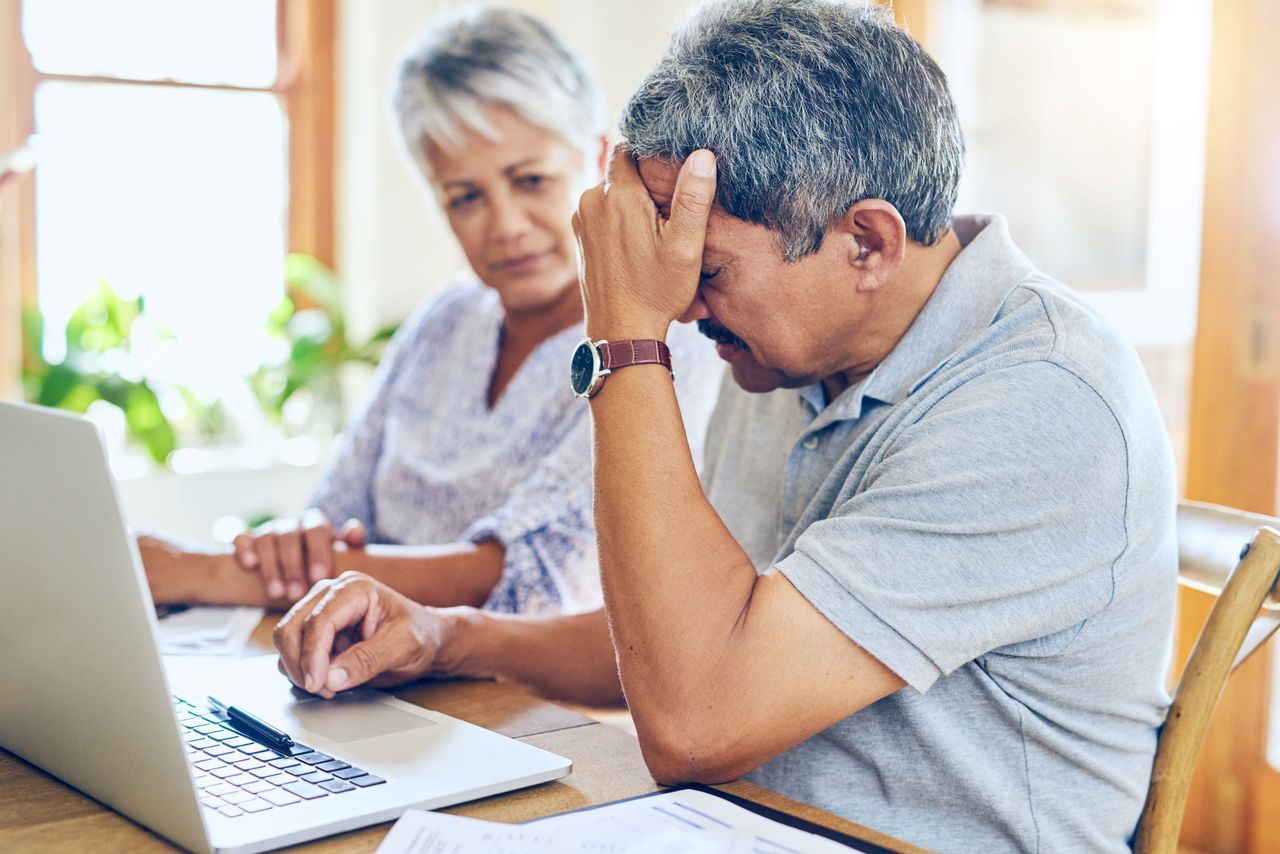 A couple looks at a computer while seeming stressed.