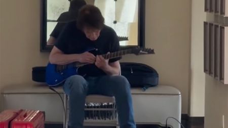 John Fogerty playing guitar with a mirror behind him