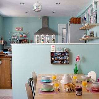 kitchen dinning area with blue wall wooden dinning table and wooden shelf