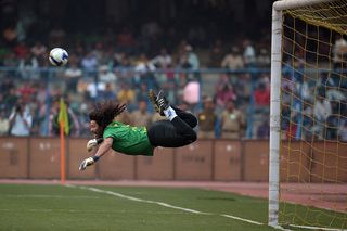 Former Colombian goolkeeper Rene Higuita kicks the ball to save a goal during an exhibition match between the Brazilian Masters and Indian All Stars in Kolkata on December 8, 2012. The Brazilian team won the match by 3-1. AFP PHOTO/ Dibyangshu SARKAR (Photo credit should read DIBYANGSHU SARKAR/AFP via Getty Images)