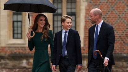 Prince George and the Prince and Princess of Wales walk through a courtyard at Eton