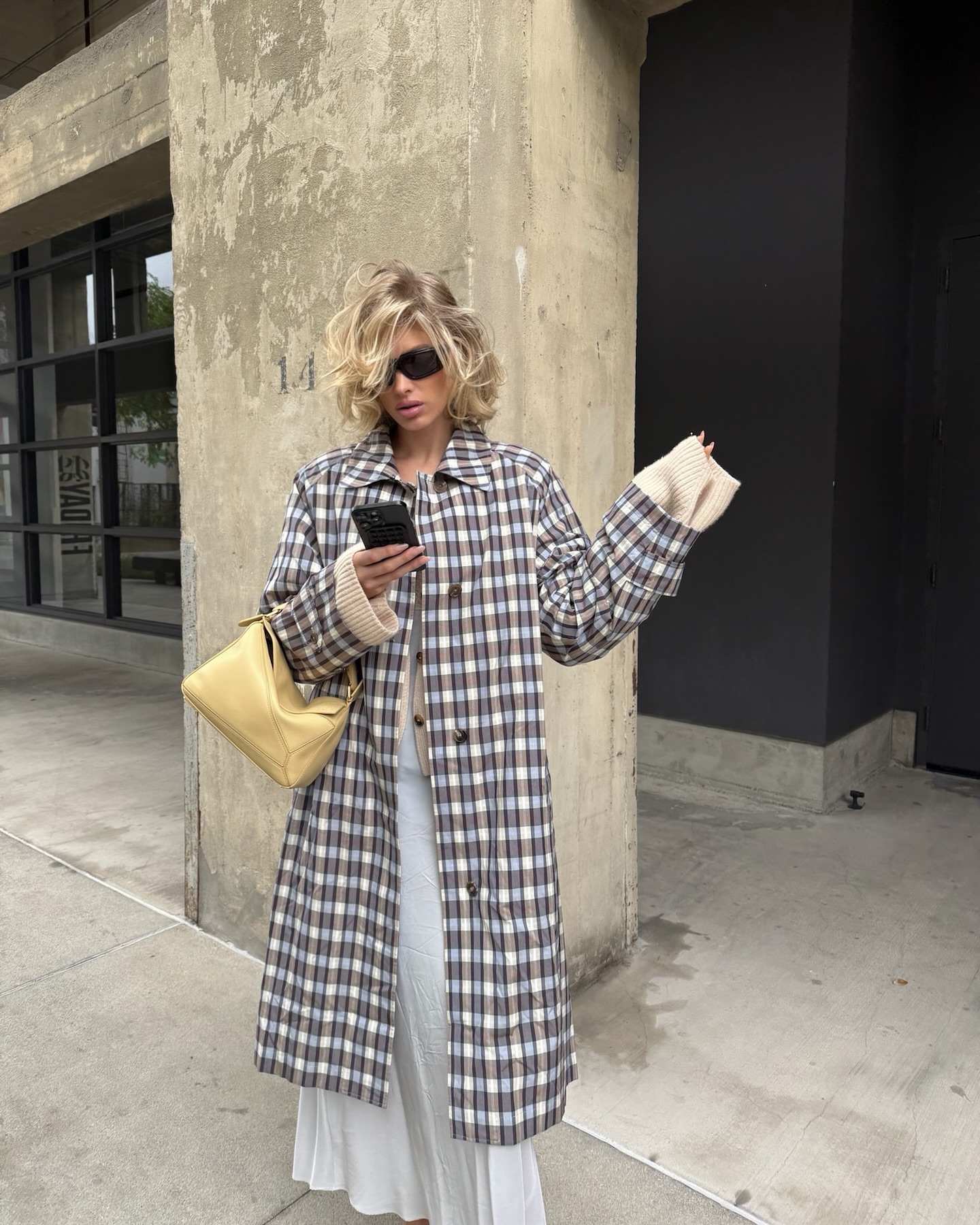 Elsa wears a plaid jacket, white skirt, and butter yellow bag.