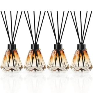 A set of 4 glass orange reed diffusers with black lid, black reeds and gold leaf detail