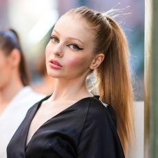 Sorina Stanciu wears winged eyeliner and a black lown-neck v-neck dress, during the Ramelle show, during "Feeric" Fashion Week 2021 In Sibiu, on July 23, 2021 in Sibiu, Romania. 