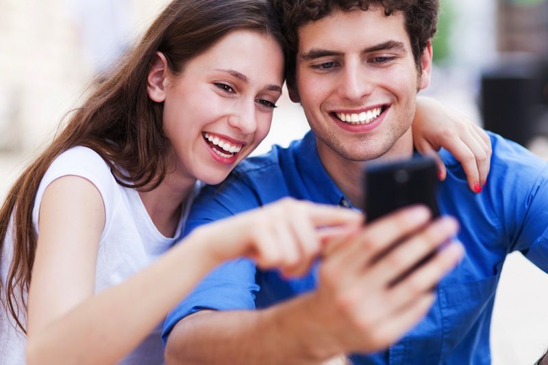 A young couple takes a picture of themselves using a smartphone.