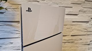 A close up of the PlayStation symbol at the top of a PS5 Slim console with a white brick background