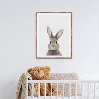 framed print of a rabbit looking down on a baby's cot