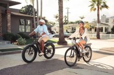 A man and a woman riding side by side on a road on their Aventon bikes.