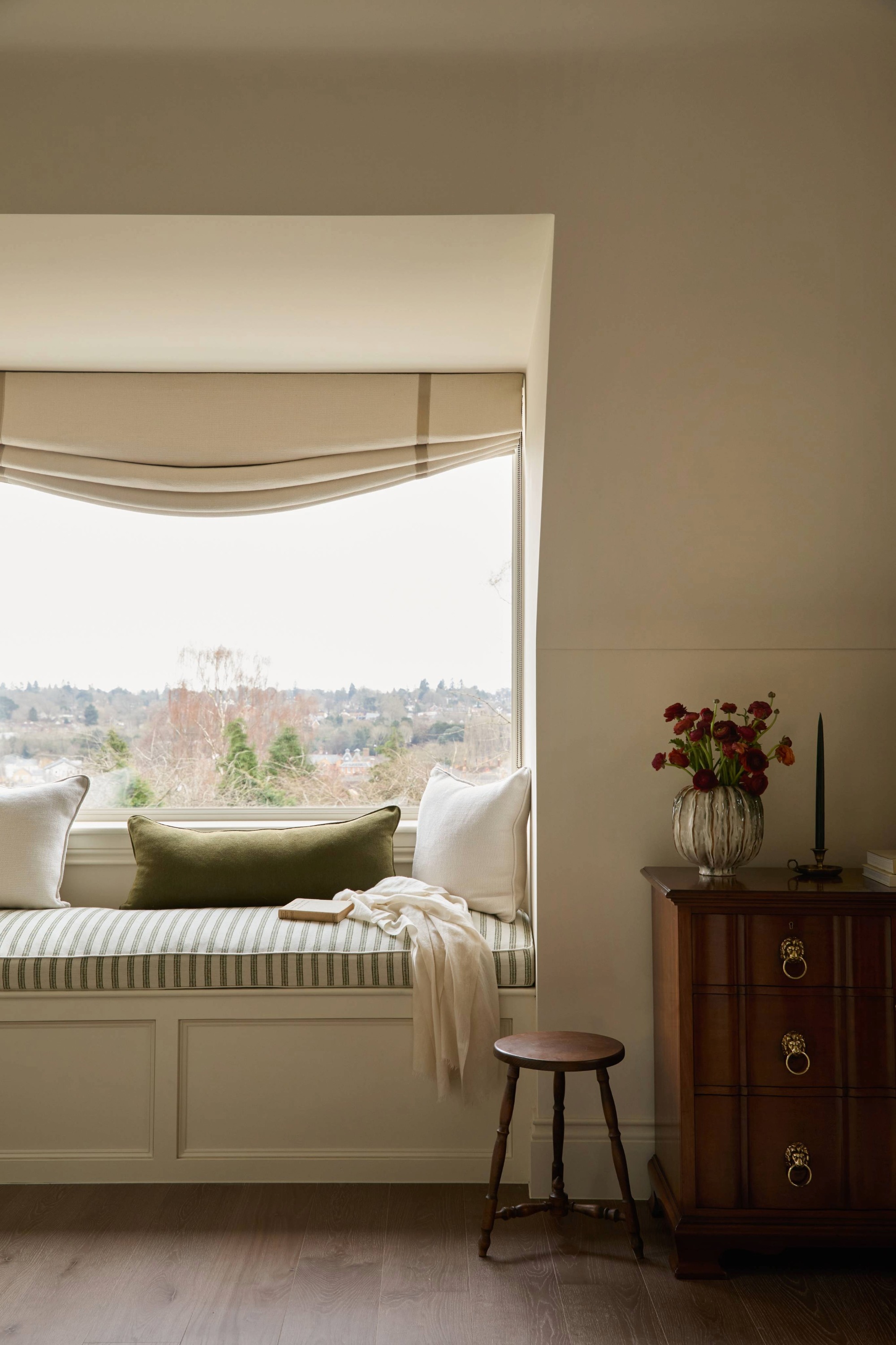a window seat with an upholstered bench and roman blind